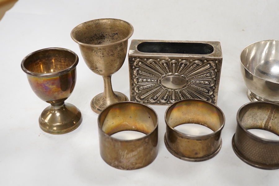 Sundry silver, consisting of - a modern tea strainer and stand, bu C.J. Vander Ltd, an egg cup, small goblet, three serviette rings, a stand and a match box case.
